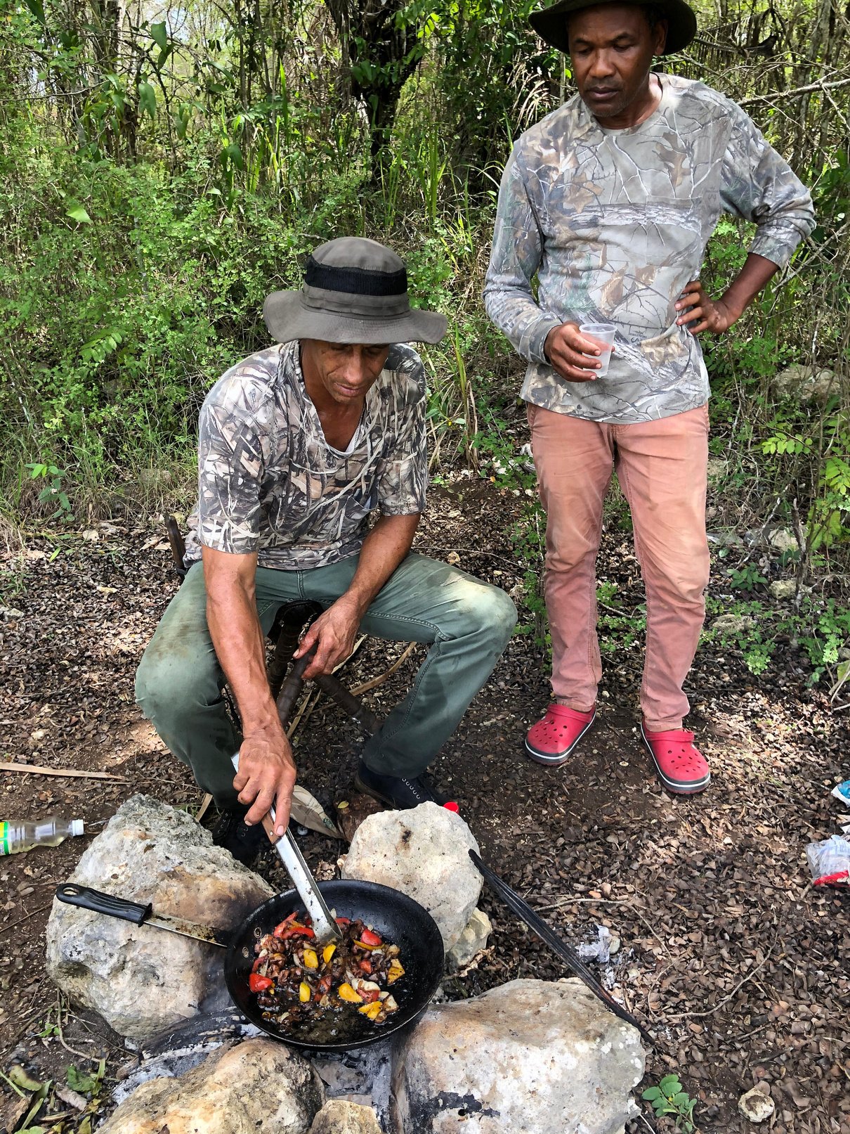 Two Jamaican hunters silhouetted against a dawn sky with a Labrador retriever