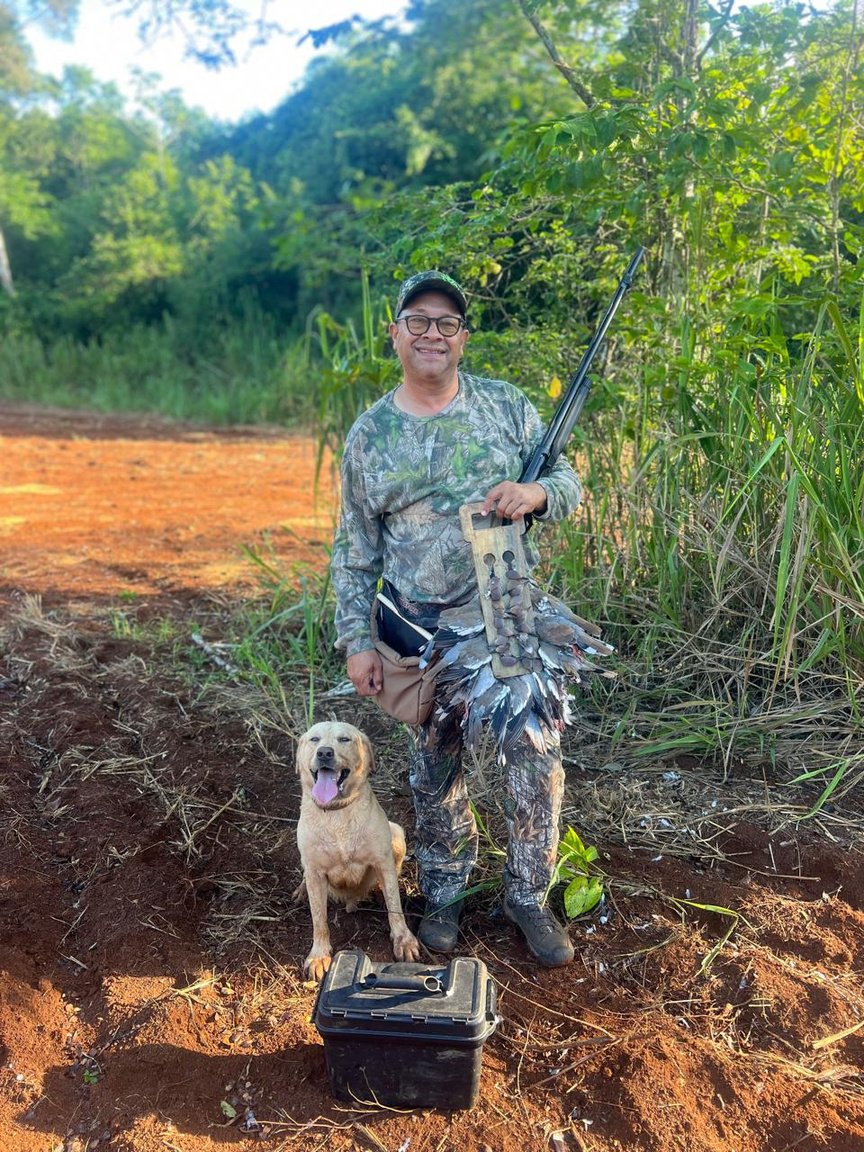 A lively outdoor bush cookout with hunters and community gathered around a fire