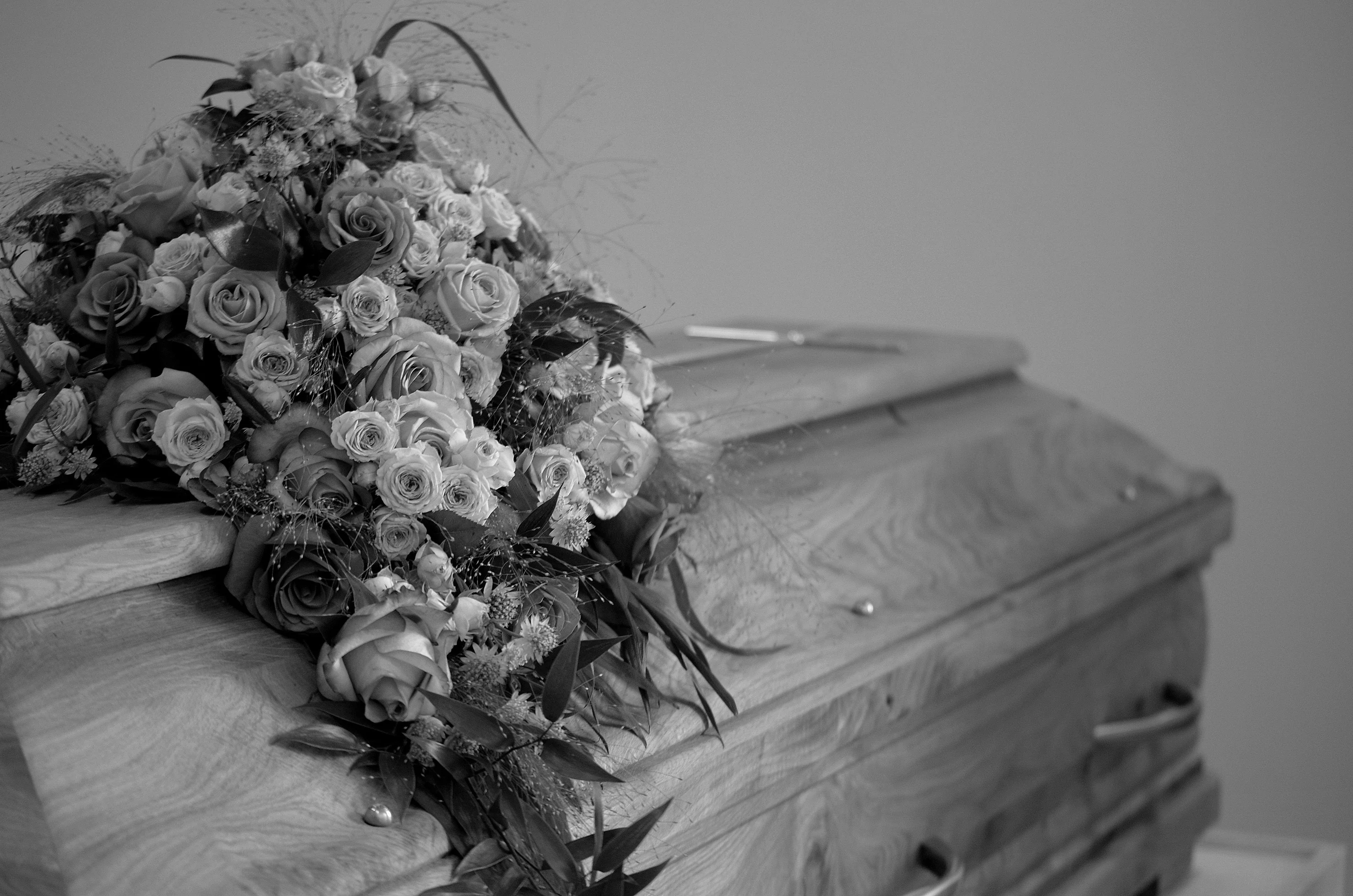 High-end still life of a polished mahogany luxury casket with soft white lilies