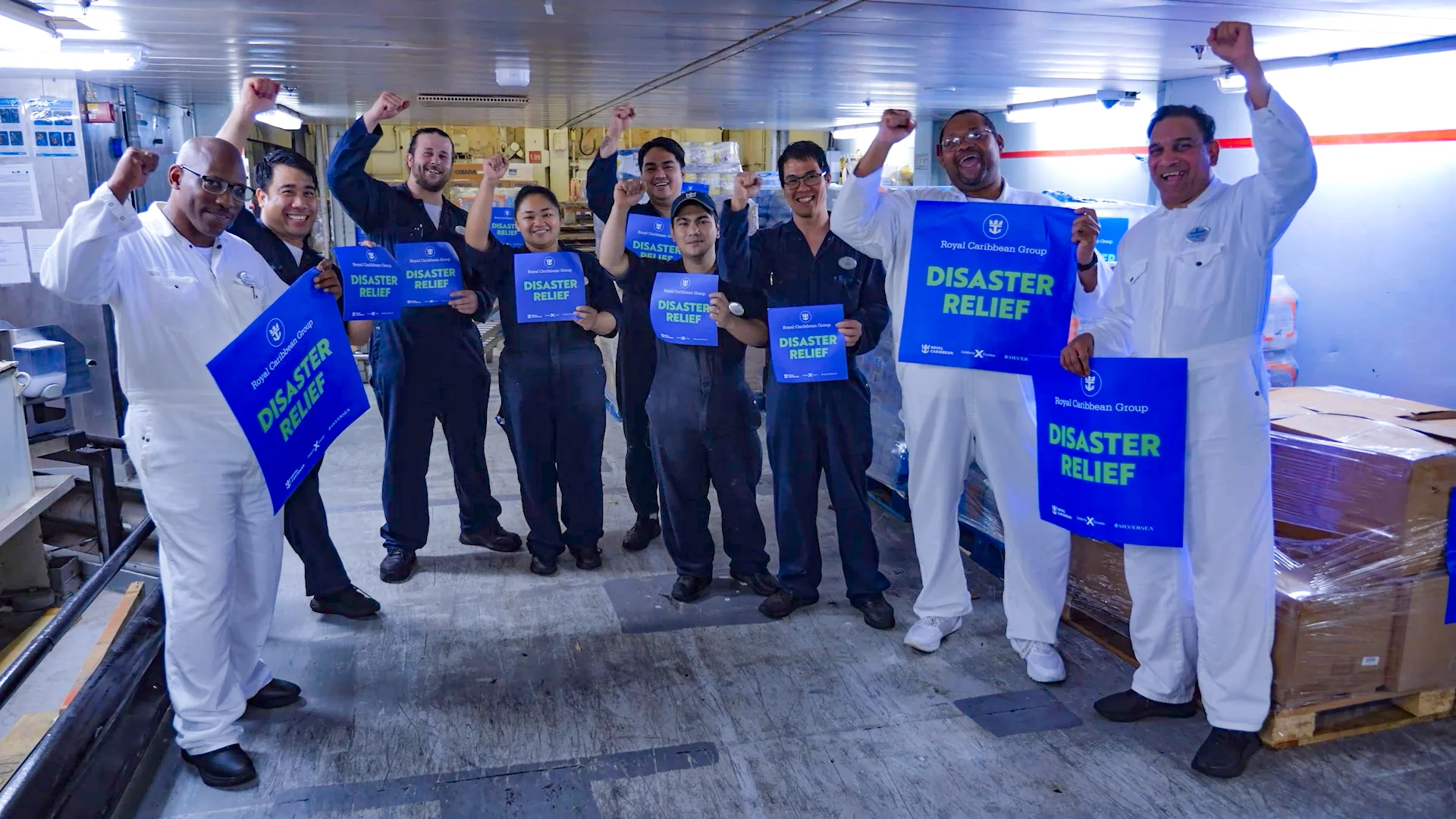 Crew members passing boxes of relief supplies from ship to shore